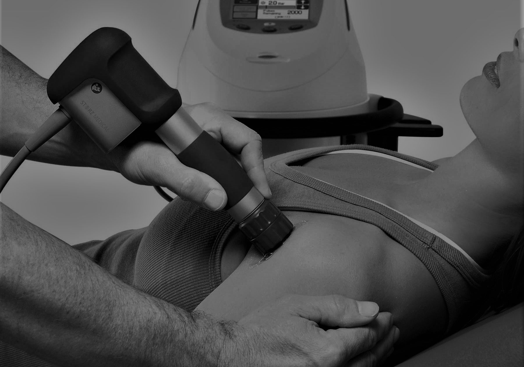 Shockwave therapy machine applying treatment on a woman's shoulder